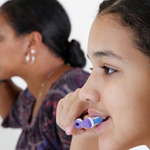 Young girl brushing her teeth with toothpaste as part of cavity prevention routine.