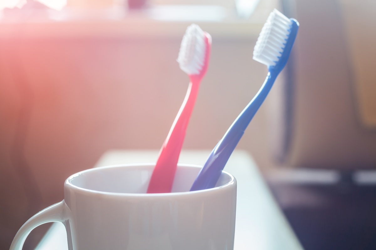 How Often Should You Change Your Toothbrush Two toothbrushes inside a white ceramic cup