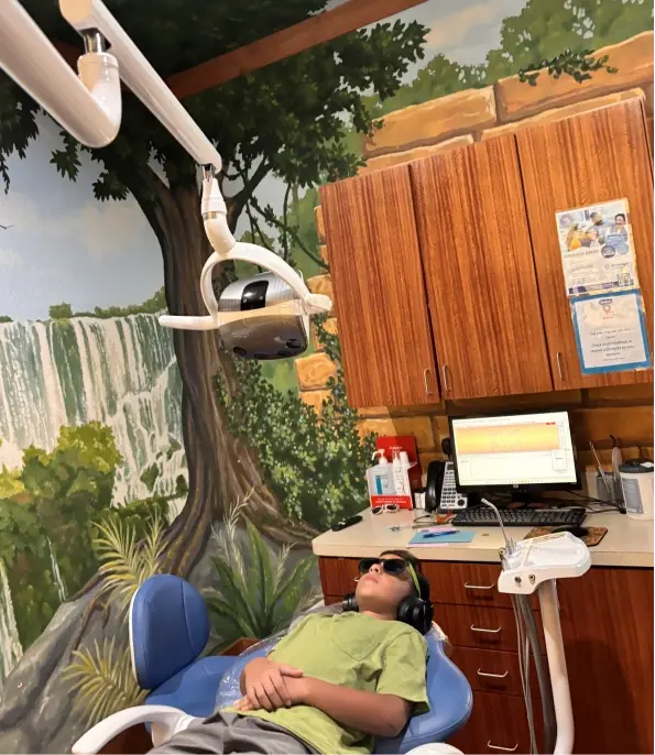 Young patient relaxed in dental chair under overhead light during treatment at McKinney dental practice.