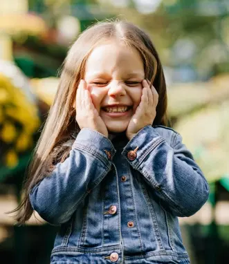 Happy young girl smiling with hands to face during preventive dental care visit in McKinney.