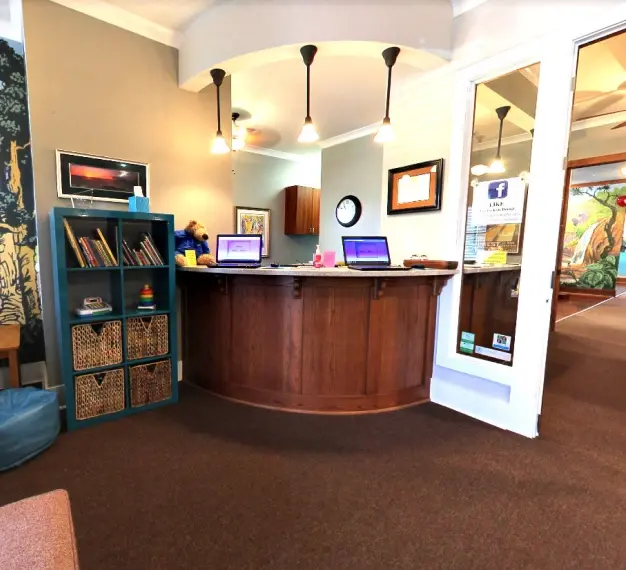 Modern dental office reception area with curved wooden desk, pendant lighting, and professional décor.