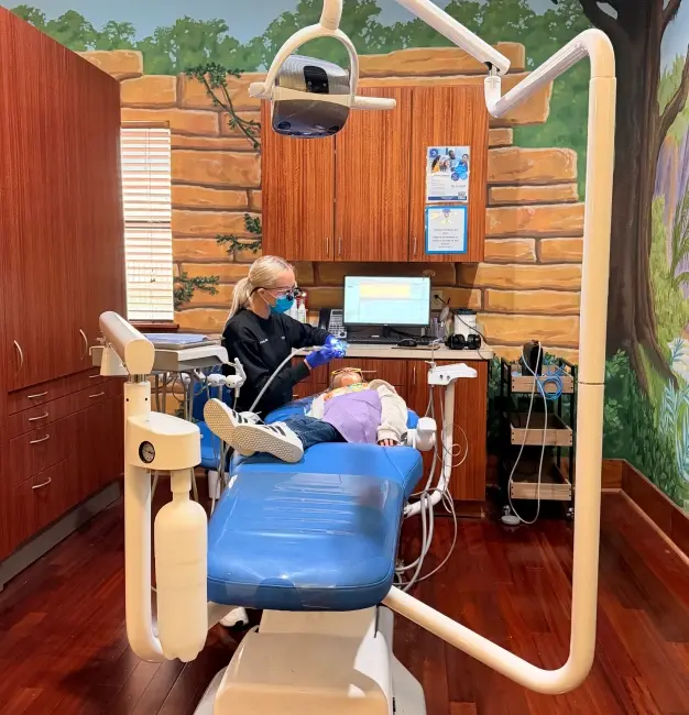 Dental hygienist treating patient in modern operatory with log cabin interior design at McKinney practice.