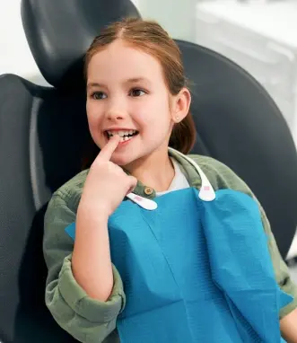 Happy child in dental bib relaxing in chair during sedation dentistry visit.