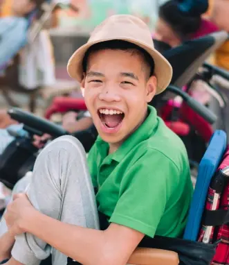 Happy young patient in green shirt and white hat smiling at dental practice in McKinney.