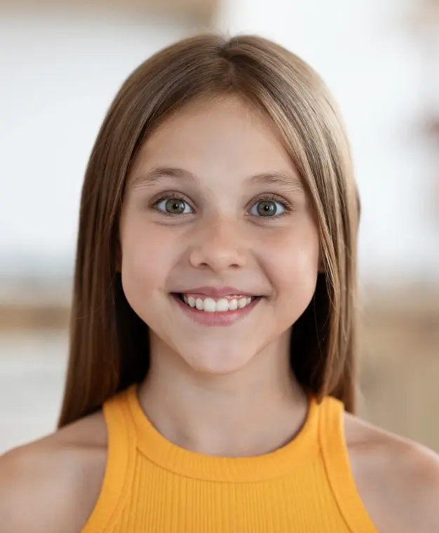 Smiling young woman with whitened teeth wearing a yellow top.