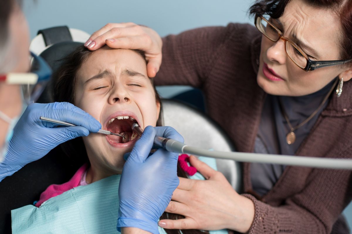 Pediatric dentist examining a child with a toothache during an emergency dental visit in McKinney TX